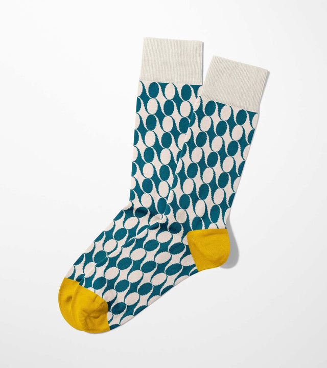 A digital mockup of petrol geometric pattern socks with yellow toe and heels, on a light grey background.