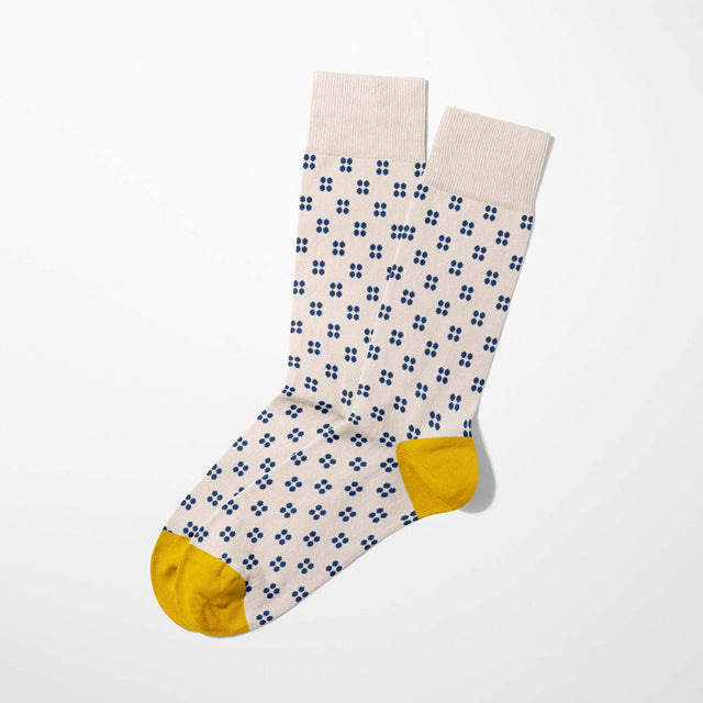 A digital mockup of small blue dots socks with yellow toe and heels, on a light grey background.