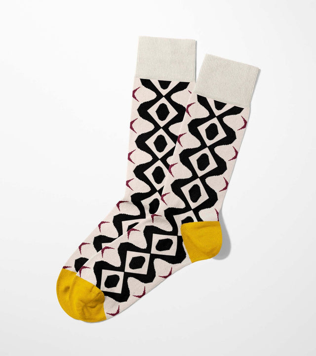 A digital mockup of black bold geometric pattern socks with yellow toe and heels, on a light grey background.