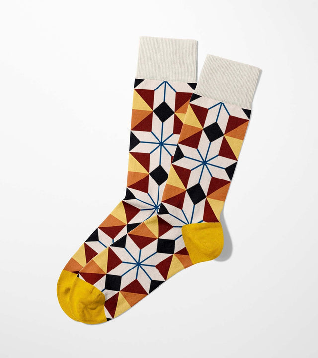A digital mockup of colored geometric socks with yellow toe and heels, on a light grey background.