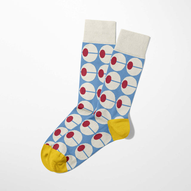 Inspired by Portuguese modernism, the unisex Olhão socks feature blue fabric with white and red circles, cream cuffs, and yellow heels and toes, displayed flat on a white background.